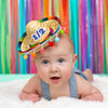 Baby wearing multi pom mini straw hat with royal blue number "1/2".